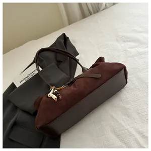 Détail du sac à bandoulière en daim marron foncé avec des perles en bois sur la poignée