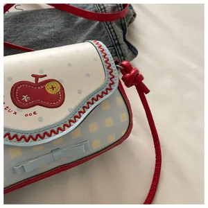 Detail of cute apple-themed crossbody bag with cherry embroidery and blue polka dot lace