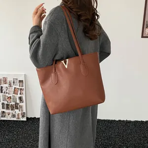Große braune Leder-Tote-Tasche mit goldenem V-Metallbeschlag und langen Schulterriemen