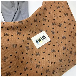 Primer plano de bolso tote de pana marrón con lazos y etiqueta de tela de marca