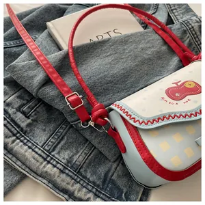 Detail of blue lace crossbody bag with red cartoon fruit print and adjustable strap