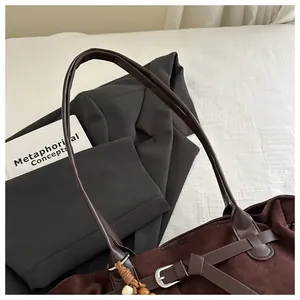 Détails d'un cabas rétro en daim marron avec sangles en cuir et boucles métalliques argentées