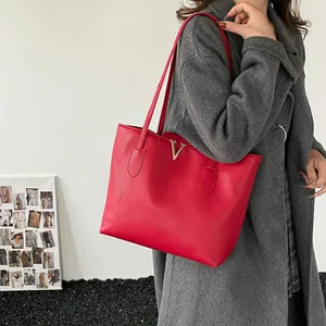 Große rote Shopper-Tasche mit goldenem V-Detail und Litschi-Textur, am Model präsentiert