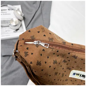 Detalle de bolso tote de pana marrón con estampados de corazones y cremallera de metal