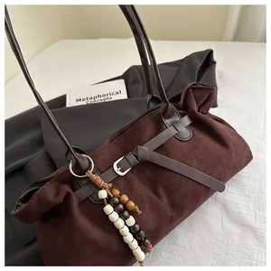 Détail du cabas en daim marron foncé avec bandoulière en cuir et breloque en perles
