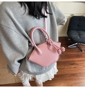 Détail d'un sac à main rose en cuir irrégulier avec décoration de nœud et bandoulière