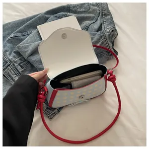 Top view of blue checkered shoulder bag with red bow and metallic magnetic buckle closure