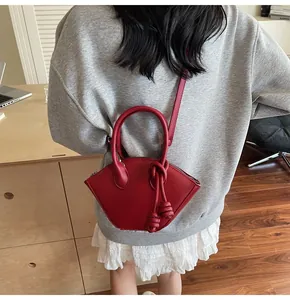 Détail macro d'un sac à main rouge en forme d'éventail avec nœuds décoratifs et texture