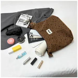 Detalle en plano de la bolsa tote de pana marrón que muestra el interior amplio con accesorios
