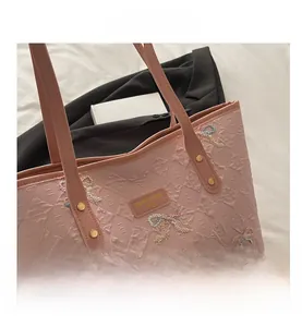 Detail of pink quilted tote bag with colorful butterfly embroidery and logo tag