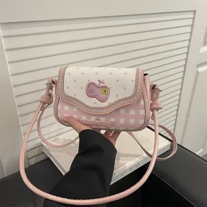 Close-up of pink apple crossbody bag with lace stitching and bow detail by handbag