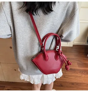 Détail du sac à main rouge en forme de coquille avec nœuds porté en bandoulière