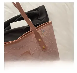 Detail of pink tote bag showing textured fabric and colorful embroidered butterfly knots