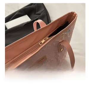 Detailed macro shot of the smooth gold metal zipper on a pink textured tote bag
