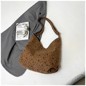 Detalle de textura del bolso tote de pana marrón con lazos negros y estampados de corazones