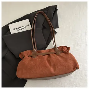 Détail du sac cabas en daim rouge rouille avec anses en cuir marron et texture plissée