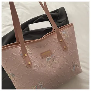 Detailed view of pink tote bag with embossed textures and delicate embroidered bows