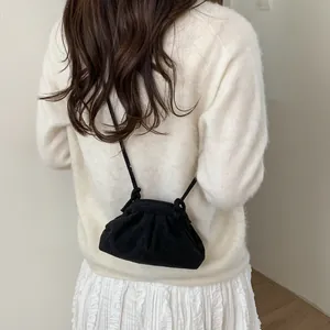 Détail d'un sac nuage noir plissé avec de fines bretelles porté sur une robe blanche