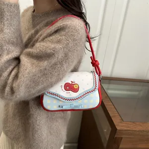 Detail of cute shoulder bag with lace edges, cherry embroidery, and blue bow details