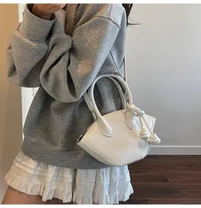 Gros plan d'un sac à main blanc en forme de coquille avec des détails noués