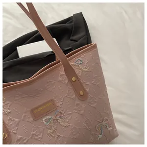 Detail of pink tote bag showing quilted texture with glitter bow and gold rivets