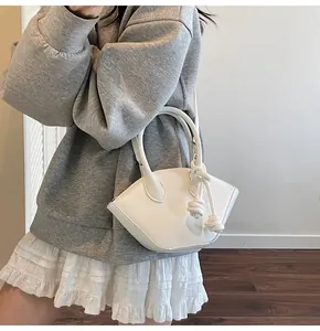 Détail du sac à main blanc avec pendentif tissé et doubles poignées présenté par un mannequin