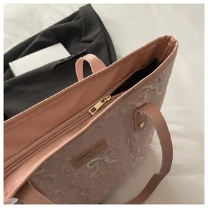 Detail of pink tote bag showing bow embroidery, gold zipper and luxury fabric texture