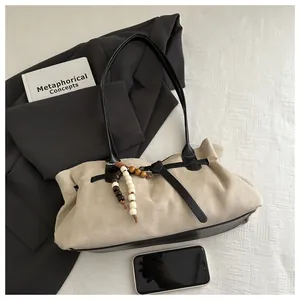 Détail macro du sac beige en daim avec perles décoratives et lanières noires
