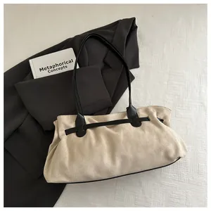 Détail macro du sac cabas en daim beige avec lanière décorative noire sur fond textile