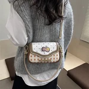 Detail of crossbody bag with floral lace, dots, orange plaid, and bow decoration