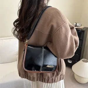 Sac à bandoulière vintage en cuir verni noir avec liseré marron et coutures contrastées