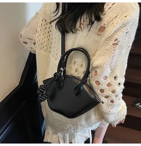Sac bandoulière chic en forme de coquille noire avec nœud décoratif porté par un modèle