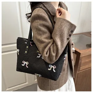 Detail of black tote bag with colorful butterfly embroidery and textured fabric finish