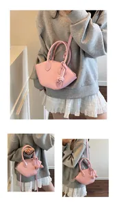 Détail du sac bandoulière rose clair avec nœud décoratif et poignée ronde rigide