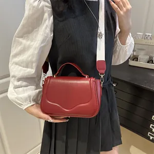Detail view of red saddle bag with wavy flap design and white wide fabric strap