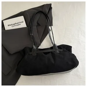 Détail du sac bandoulière en daim noir avec plis élégants et fines lanières en cuir