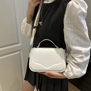 White leather handbag with unique wave-shaped flap and adjustable canvas shoulder strap