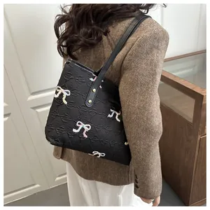 Detail of black embossed tote bag with colorful embroidered bows and gold rivets