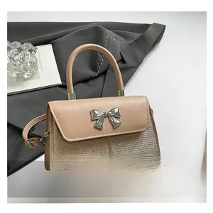 Detailed shot of khaki handbag with silver bow accent and adjustable shoulder strap