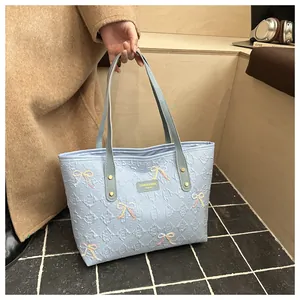 Close-up of light blue tote bag with diamond texture, letter patterns and bow charms