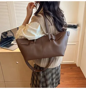 Détail du sac cabas marron foncé avec nœud décoratif et longue bandoulière