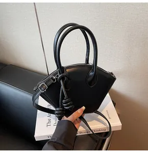 Détail du sac à main noir en forme d'éventail avec poignées argentées et pompon en cuir