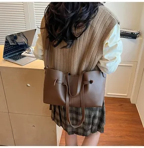 Détail d'un sac cabas en cuir mat marron foncé avec cordon sur un fond de bureau en bois