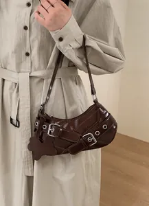 Close-up of dark brown underarm bag with punk metal buckles and dog-shaped charm detail