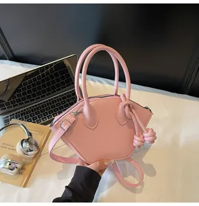 Détail du sac à main géométrique en cuir rose avec poignées et bandoulière amovible