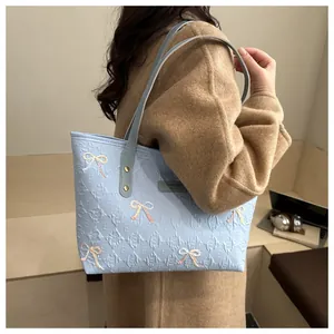 Close-up of light blue quilted tote bag with embossed textures and sequin bow detail