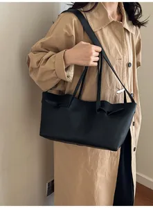 Sac fourre-tout noir chic porté par un mannequin avec un trench-coat de ton neutre