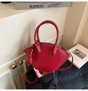 Vue détaillée du sac à main rouge foncé en forme de coquille avec noeud décoratif