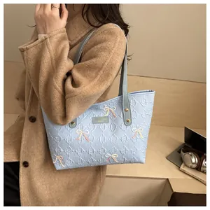 Detailed embroidery bow patterns on light blue tote bag with elegant embossed texture