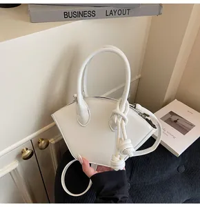 Vue détaillée du sac coquille en cuir blanc avec bandoulière à nœud au style minimaliste
